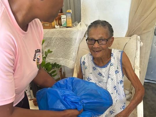 Voluntaria entregando una funda de alimentos a una señora mayor sonriente