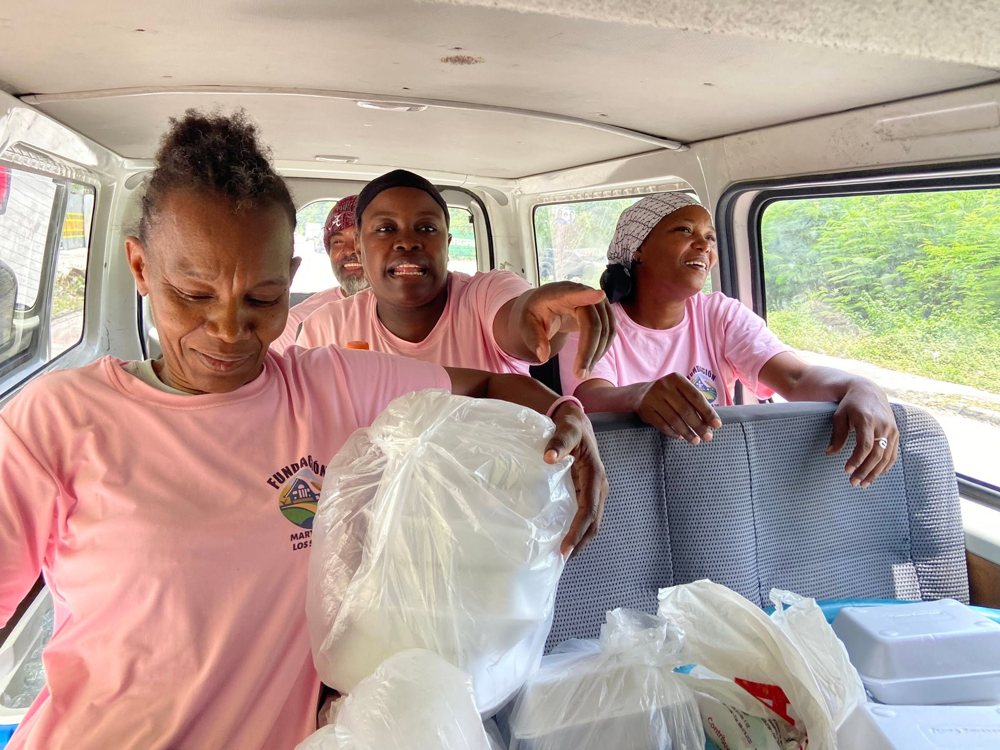 Voluntarias de la fundación, con camisetas rosadas, de camino a una jornada con las comidas preparadas