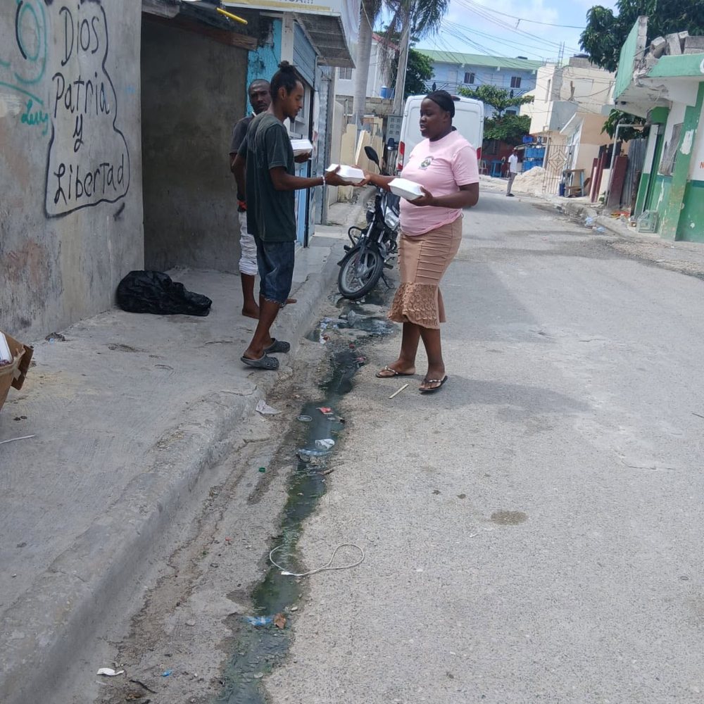 Voluntaria entregando comida en la calle de un barrio