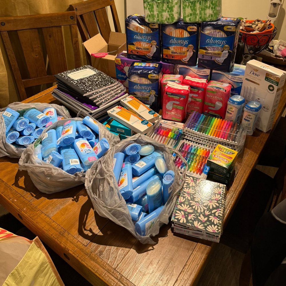 Mesa llena de donaciones: artículos de higiene, cuadernos, lápices y colores