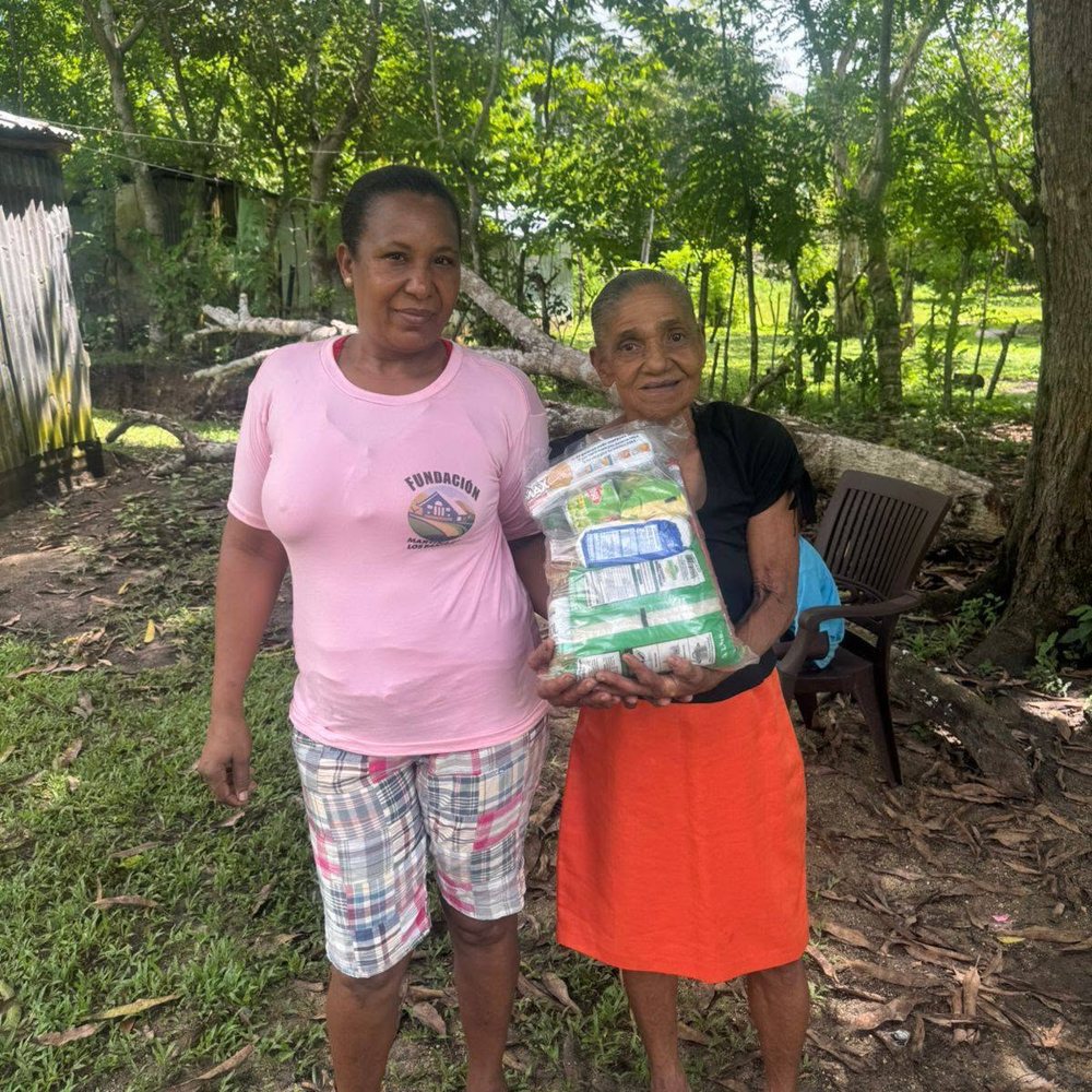 Voluntaria de la fundación junto a una señora mayor que recibe una funda de alimentos